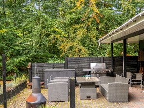 Una terrazza esterna con mobili in vimini, un barbecue e un camino.