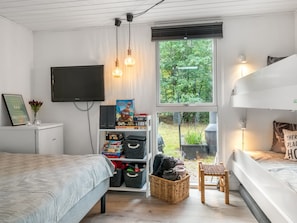 A bedroom with a bed, a TV, a bookshelf, and a window with a view of greenery. - "Nanook" -  from the sea by Interhome (Hadsund)