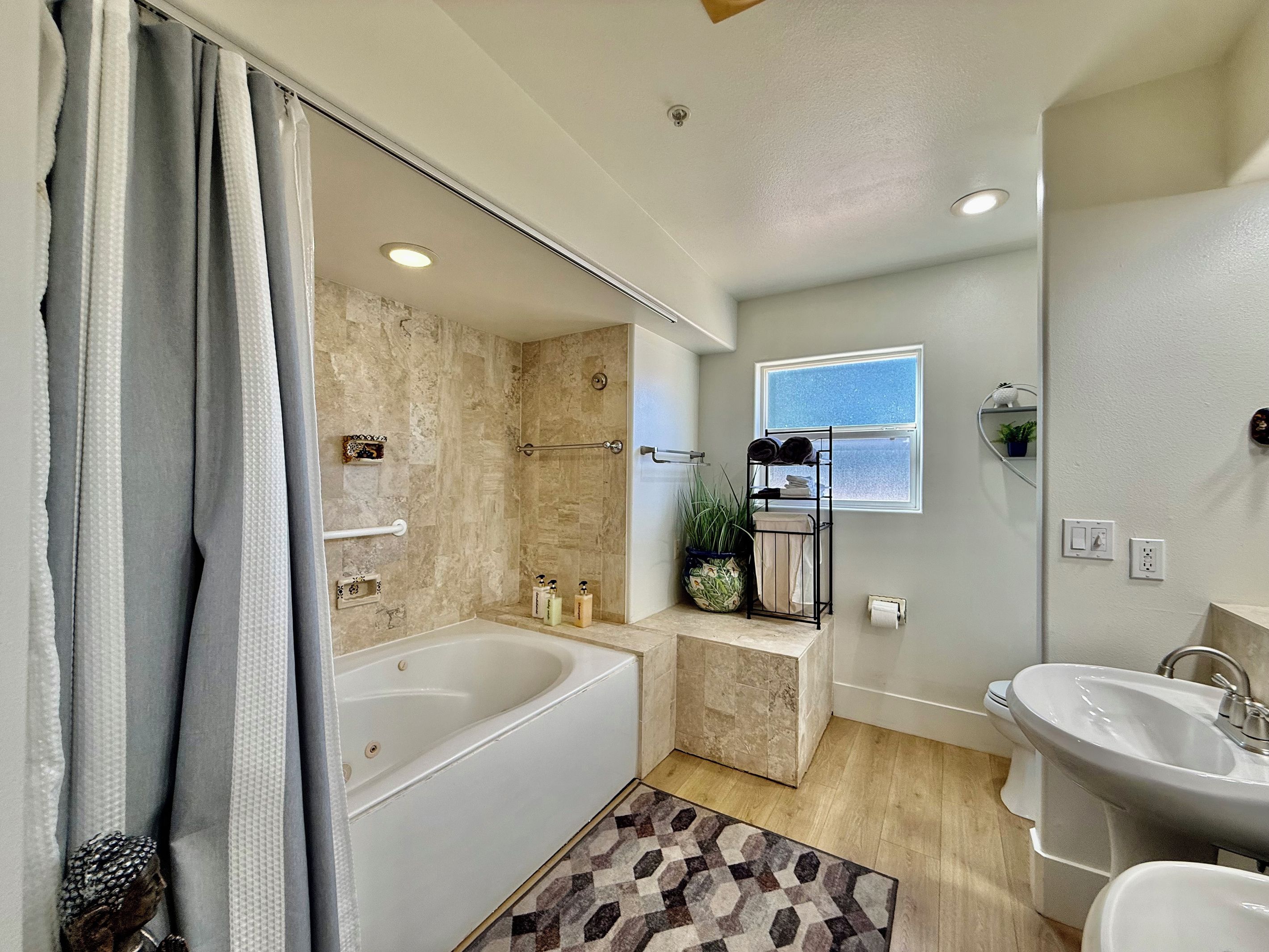 A modern bathroom with a bathtub, a sink, and a shower area.