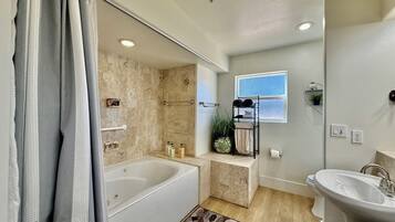 A modern bathroom with a bathtub, a sink, and a shower area.