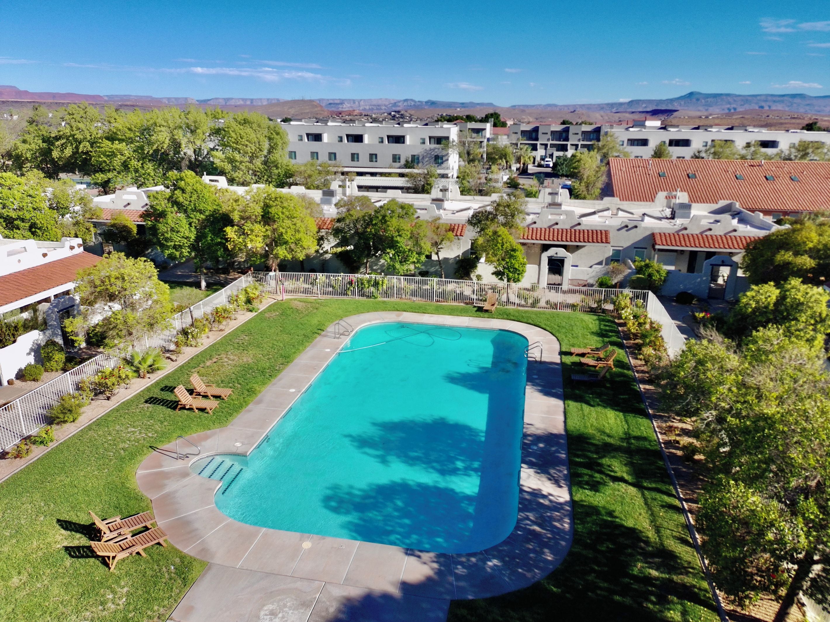 A residential area with a swimming pool, houses, and a mountainous backdrop.