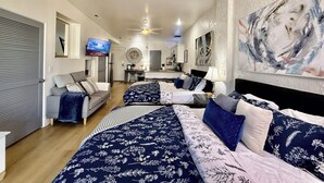 A hotel room with a bed, a sofa, a desk, and a television. - Tranquil Desert Retreat | Pools & Hot Tub (St George)