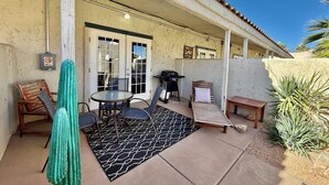 An outdoor patio with a grill, seating, and a door with a no-smoking sign. - Tranquil Desert Retreat | Pools & Hot Tub (St George)