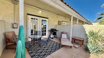 An outdoor patio with a grill, seating, and a door with a no-smoking sign.