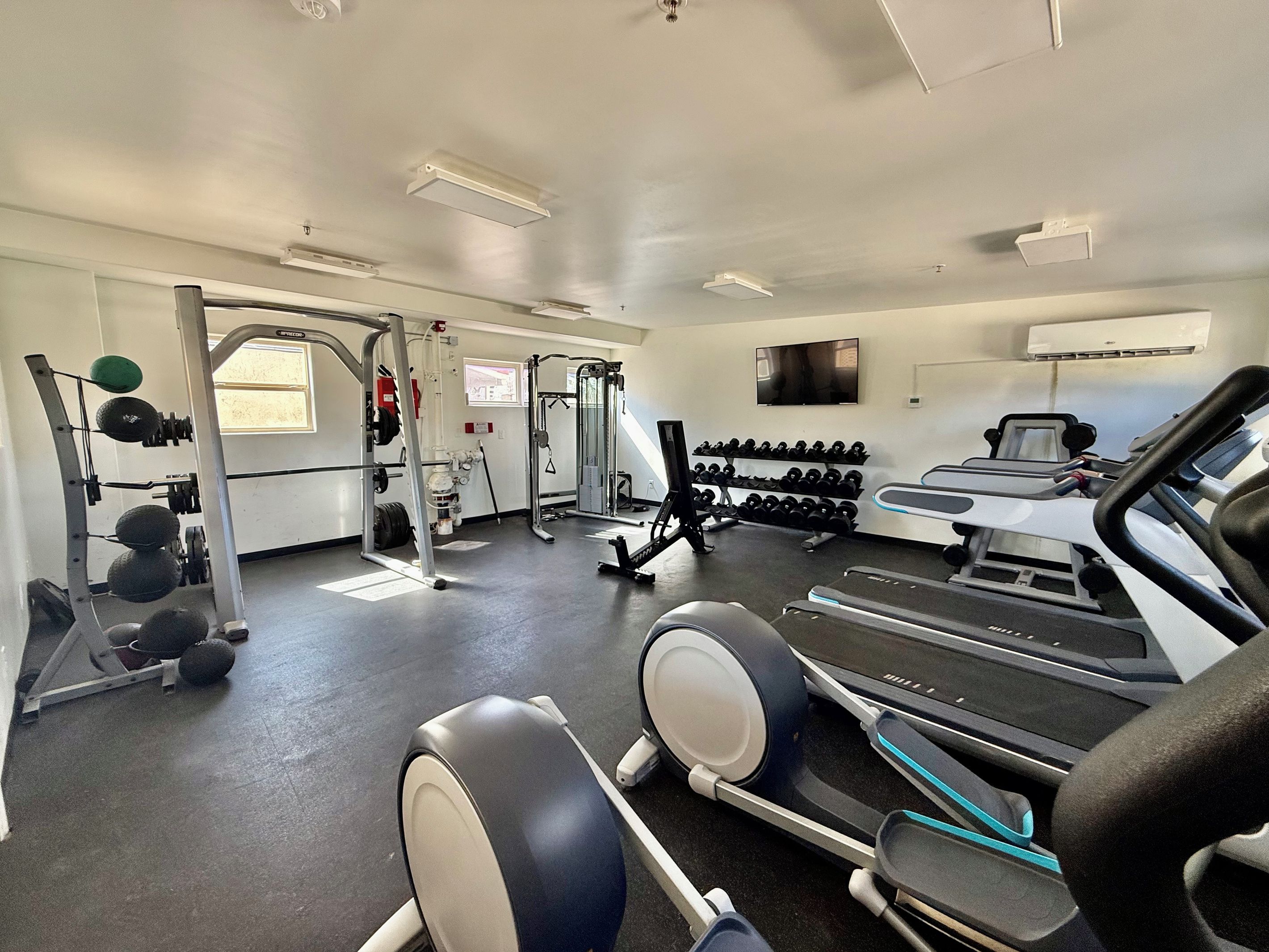 Une salle de sport équipée de tapis de course, d’appareils de musculation et d’haltères.