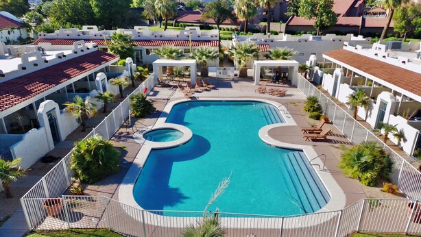A swimming pool with a fountain, surrounded by lounge chairs and a fence. - Tranquil Desert Retreat | Pools & Hot Tub (St George)