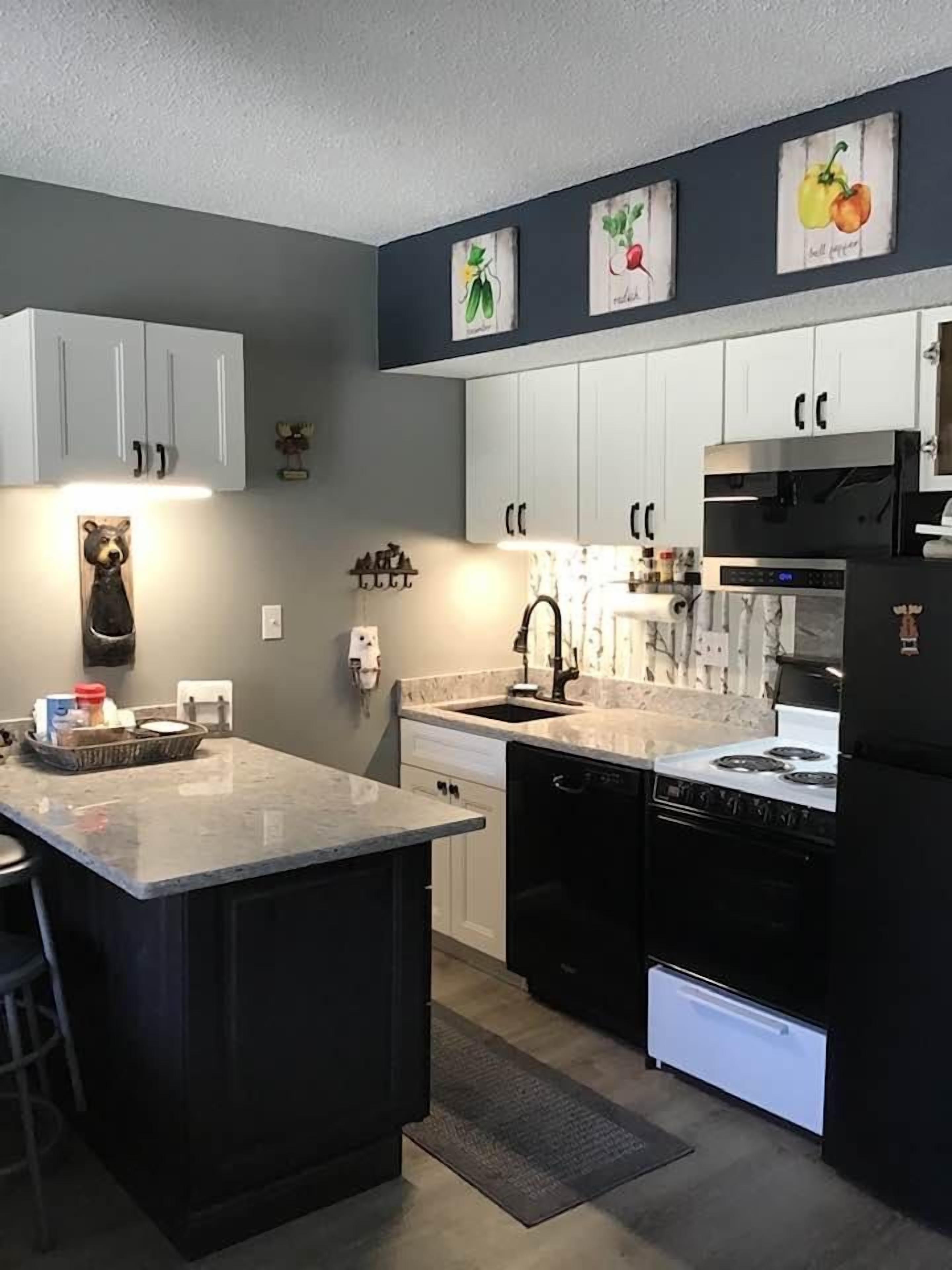 A modern kitchen with a central island, white cabinetry, and a black refrigerator.