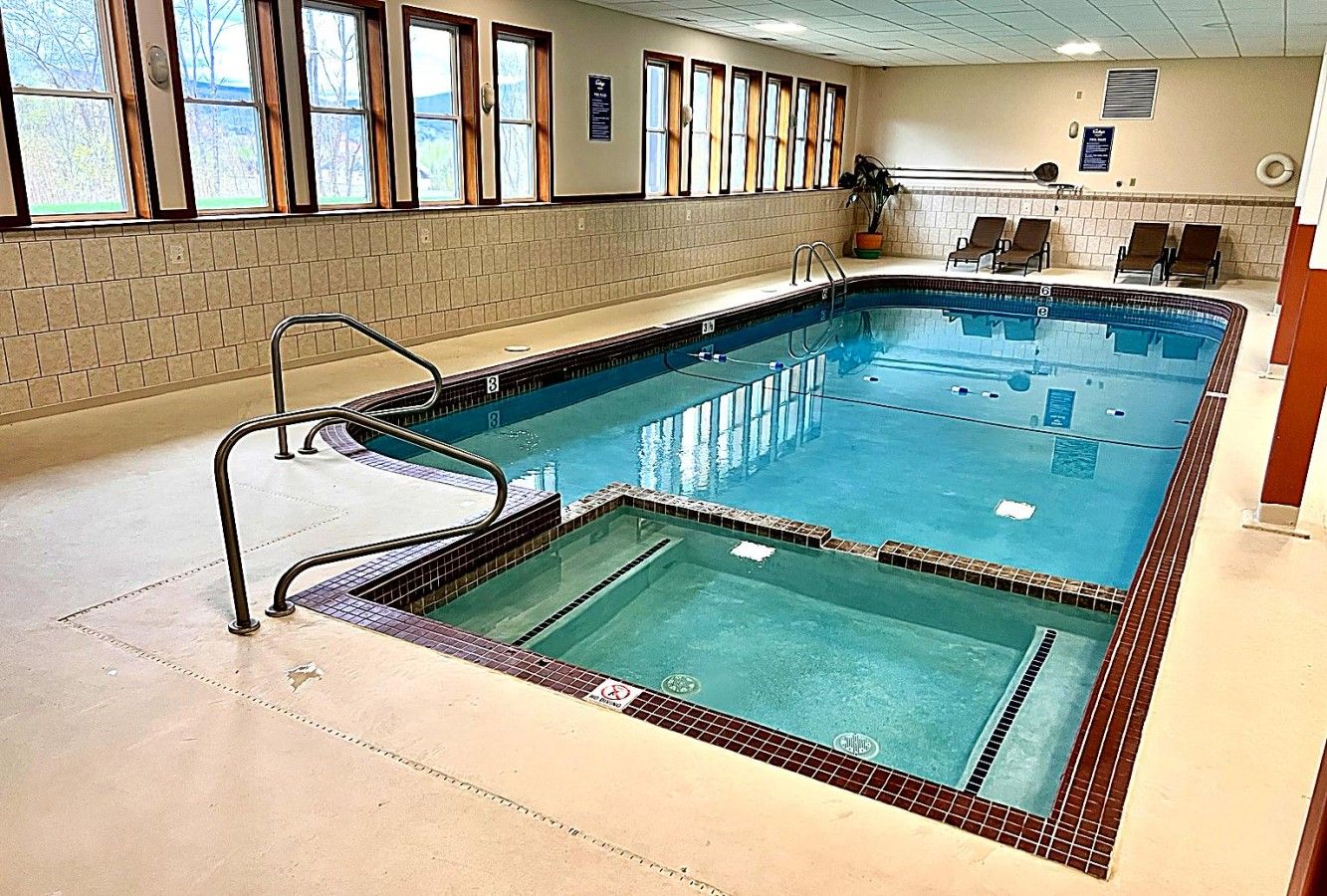 Piscina interior com borda azulejada, escada e chão revestido de azulejos.