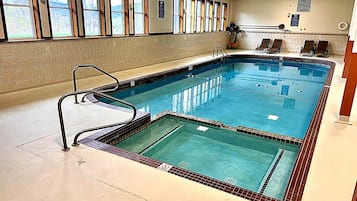 Piscina interior com borda azulejada, escada e chão revestido de azulejos.