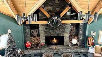 A cozy interior with a stone fireplace, wooden beams, and a Christmas tree.