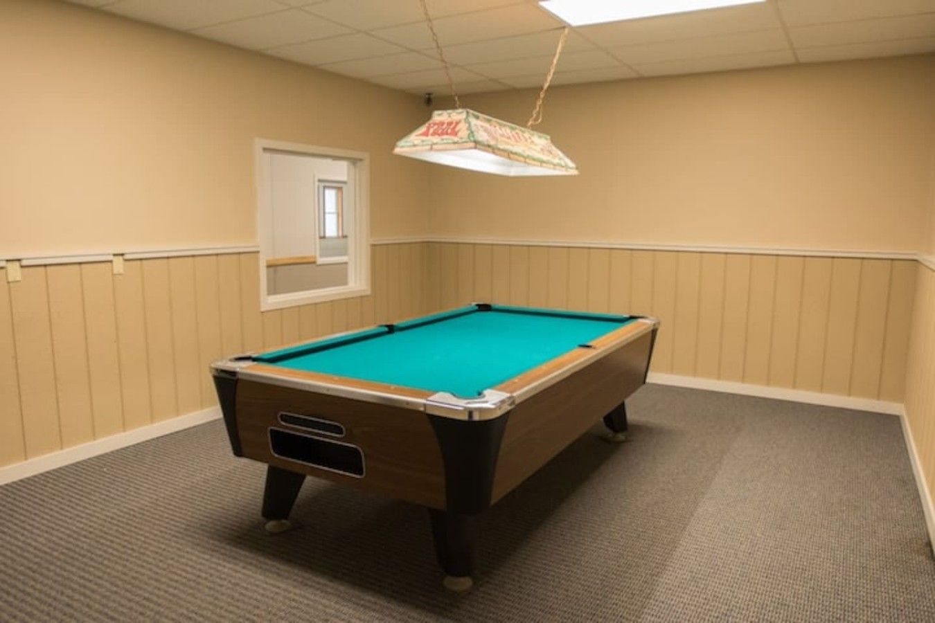 A pool table in a room with beige walls and a carpeted floor.