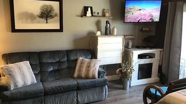 Sala de estar com sofá, televisão de tela plana, lareira e quadro na parede.