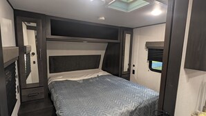 A compact bedroom with a bed, a small window, and a mirror. - Reel Escape (Scottsboro)