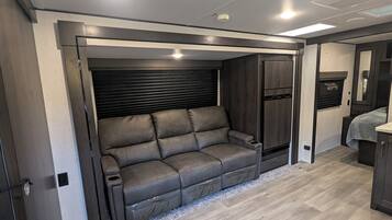 Un interior moderno con sofá, suelo de madera y luces empotradas en el techo.