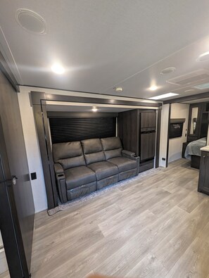 A modern interior with a sofa, wooden flooring, and recessed ceiling lights.