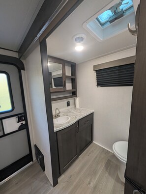 Een kleine badkamer met een wastafel, spiegel en toilet.