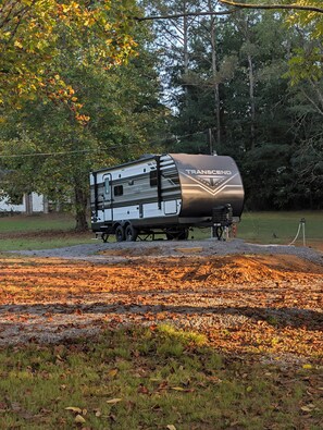 A Transcend RV parked in a grassy area with trees in the background.