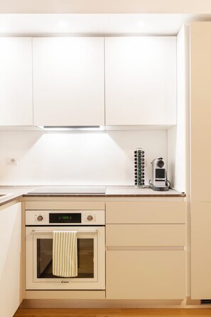 A kitchen with white cabinets, a built-in oven, a coffee maker, and a clock. - Quiet Central Flat, 2 Bedr 2 Bathrm + FREE Parking (Milano)