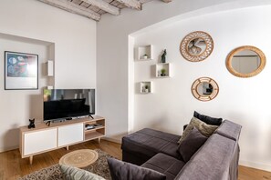 A modern living room with a flat-screen TV, a grey sofa, and a wooden ceiling. - Quiet Central Flat, 2 Bedr 2 Bathrm + FREE Parking (Milano)