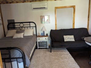 A bedroom with a bed, bedside table, lamp, and a sofa.