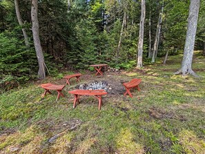 A forest clearing with a fire pit surrounded by wooden benches. - Cozy 2-bedroom cottage in serene Lakewood (Lakewood)