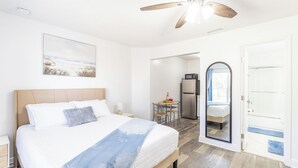 Ein Hotelzimmer mit Bett, Deckenventilator, Küchenzeile und Bad.