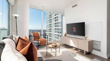 Una sala de estar moderna con sofá, sillón y televisor de pantalla plana sobre un mueble de madera.