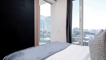 Habitación de hotel con un ventanal grande, una cama y vistas a la ciudad.