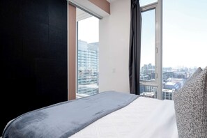 Habitación de hotel con un ventanal grande, una cama y vistas a la ciudad.