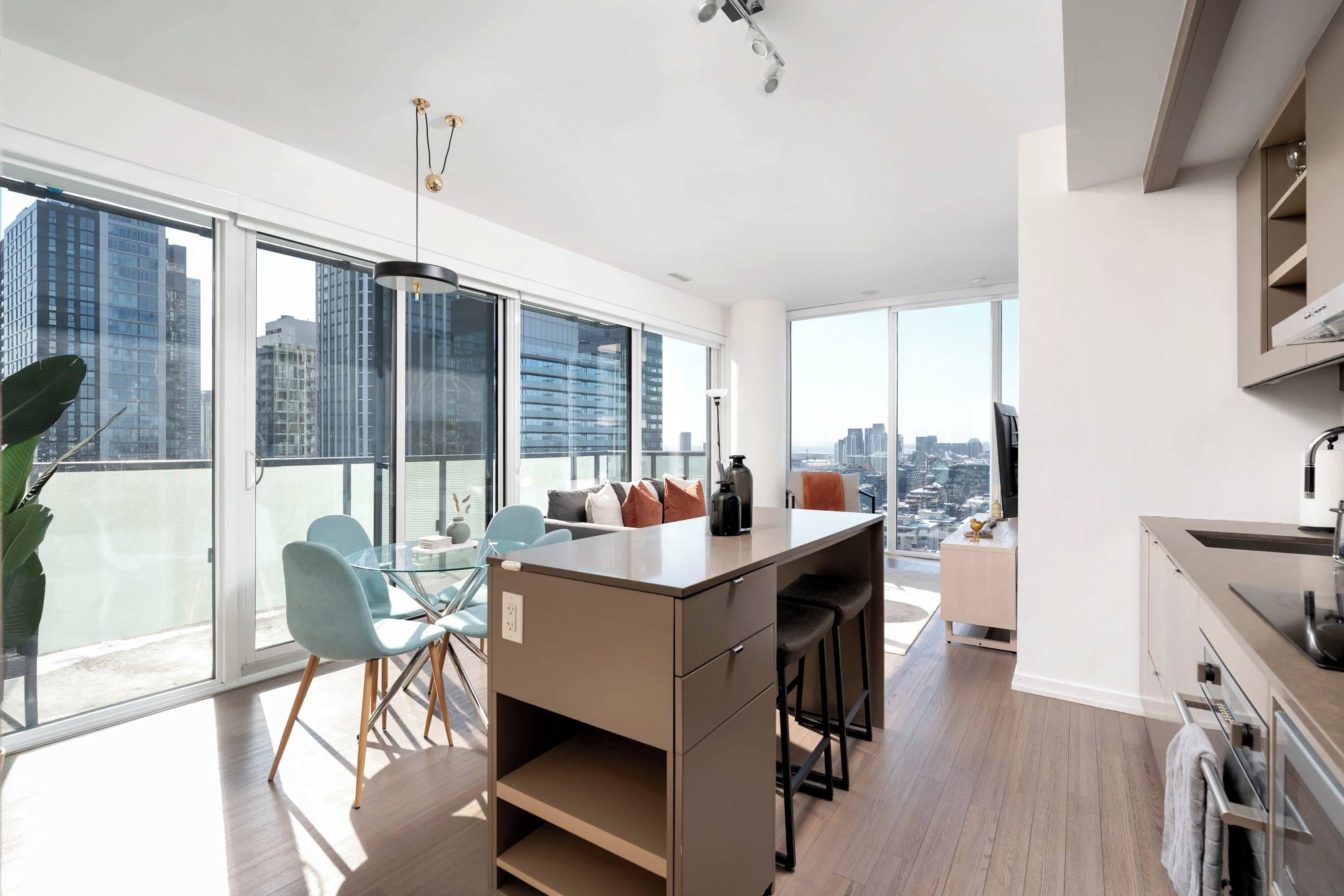 Un apartamento moderno con un balcón grande, comedor y cocina.