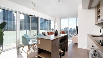 Un apartamento moderno con un balcón grande, comedor y cocina.