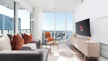 Una sala de estar moderna con un sofá, sillones, una mesa de centro y un televisor en la pared.