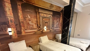 A hotel room with three beds, a large mural on the wall, and a red patterned rug. - Bella Casa Pyramids Inn (El haram)