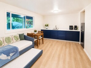 A compact living space with a sofa, dining table, and kitchen area. - Palm Paradise — AC + Gym + Game Room Sleeps 15 (Keaau)