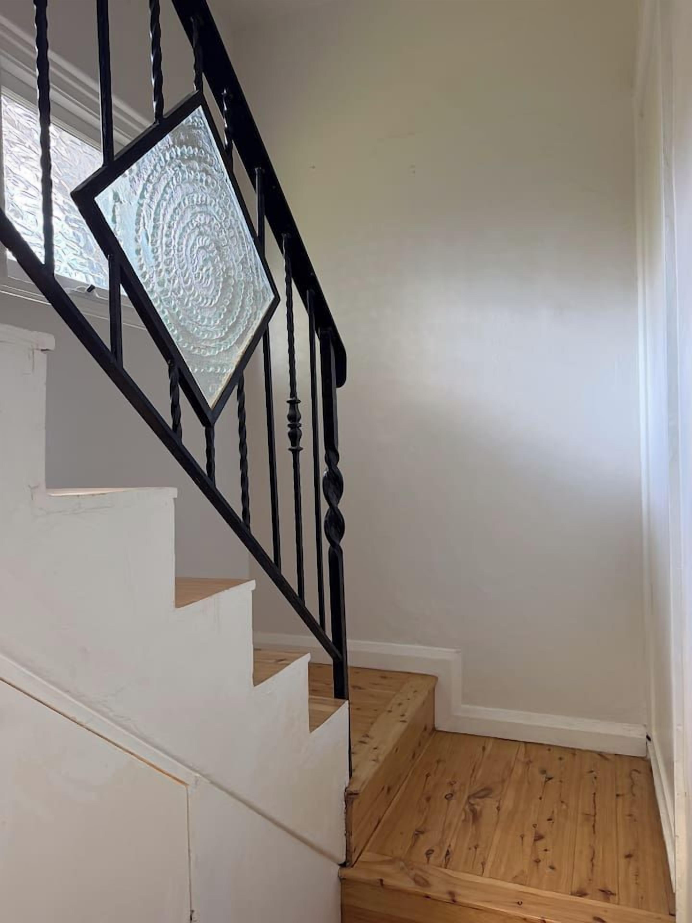 A staircase with a black railing and a white wall.