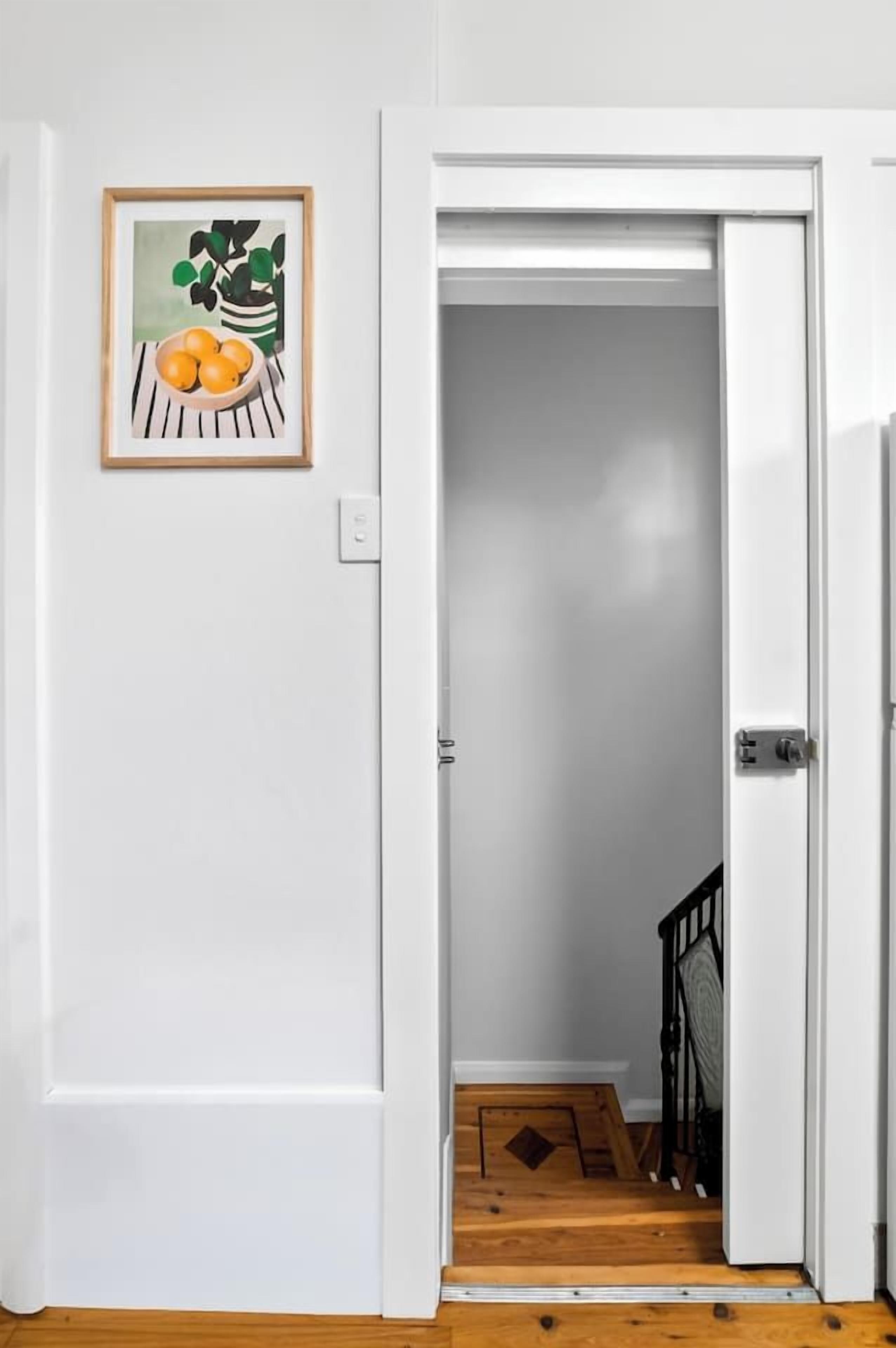 A white door leading to a room with a wooden floor and a black railing.