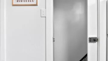 A white door leading to a room with a wooden floor and a black railing.