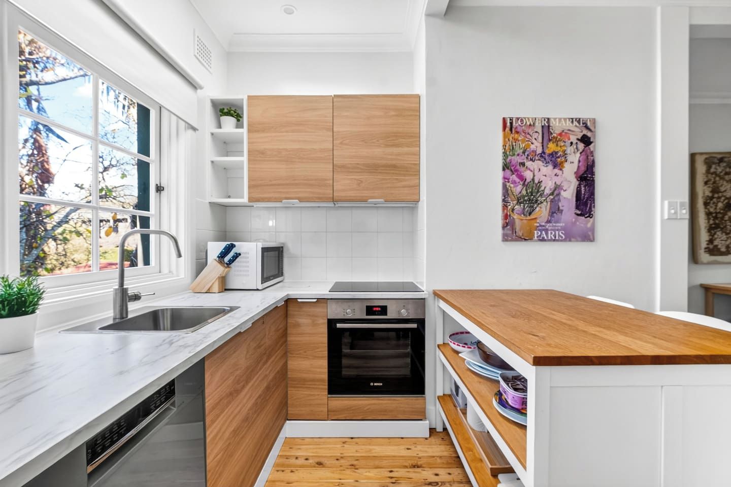 A modern kitchen with white cabinetry, a built-in oven, a microwave, and a sink.