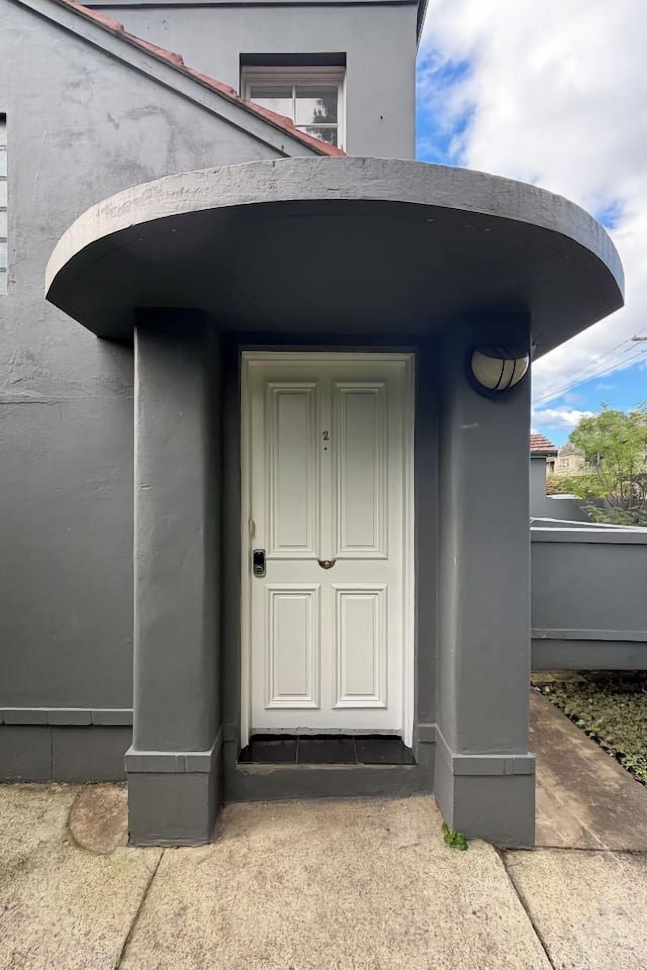 A white door with a grey overhang, a small window above it, and a basketball mounted on the wall to the right.