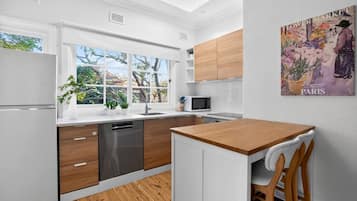 A modern kitchen with white cabinetry, a wooden countertop, and a view of the outdoors.