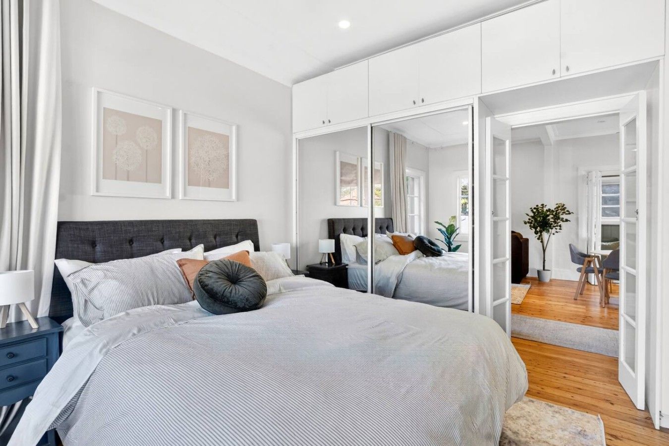 Une chambre à coucher moderne avec un grand lit, une table de chevet et un miroir.