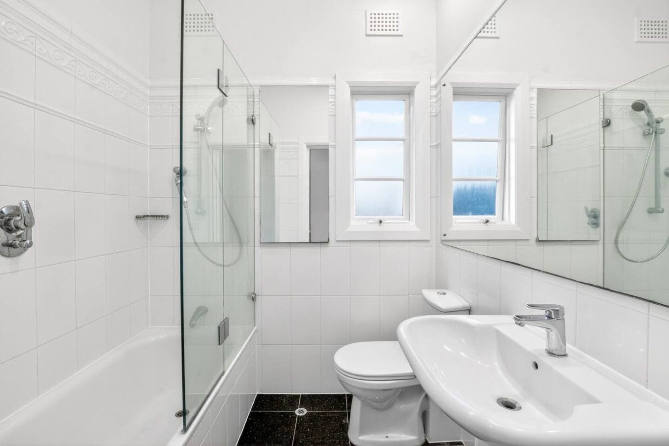 A modern bathroom with a glass-enclosed shower, a toilet, and a sink.