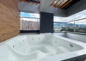 Ein modernes Badezimmer mit einer großen Badewanne, einem Oberlicht und Blick auf eine Stadtlandschaft.