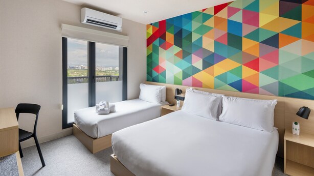 A hotel room with a bed, two bedside tables, a chair, an air conditioning unit, and a large window with a view. - Hotel101 Niseko (Abuta District)