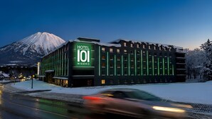 A hotel building with a prominent sign, surrounded by snow-covered trees and a mountain in the background. - Hotel101 Niseko (Abuta District)