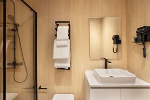 Ein modernes Badezimmer mit einer gläsernen Duschkabine, einem weißen Waschbecken und einem Handtuchhalter.
