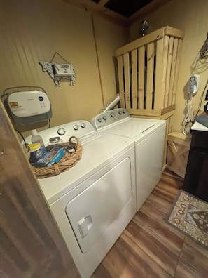 A laundry area with a washing machine, a dryer, and a small wooden cabinet. - Cozy & Quiet Getaway in the Smokies, hot tub, fire pit and more (Newport)