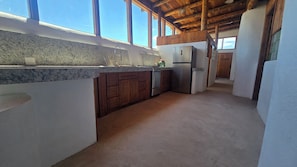 Una cocina con encimeras de granito, gabinetes de madera, refrigerador de acero inoxidable y horno empotrado.