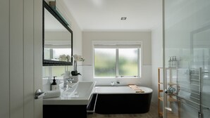 Un baño moderno con un espejo grande, una bañera y una cabina de ducha con paredes de vidrio.