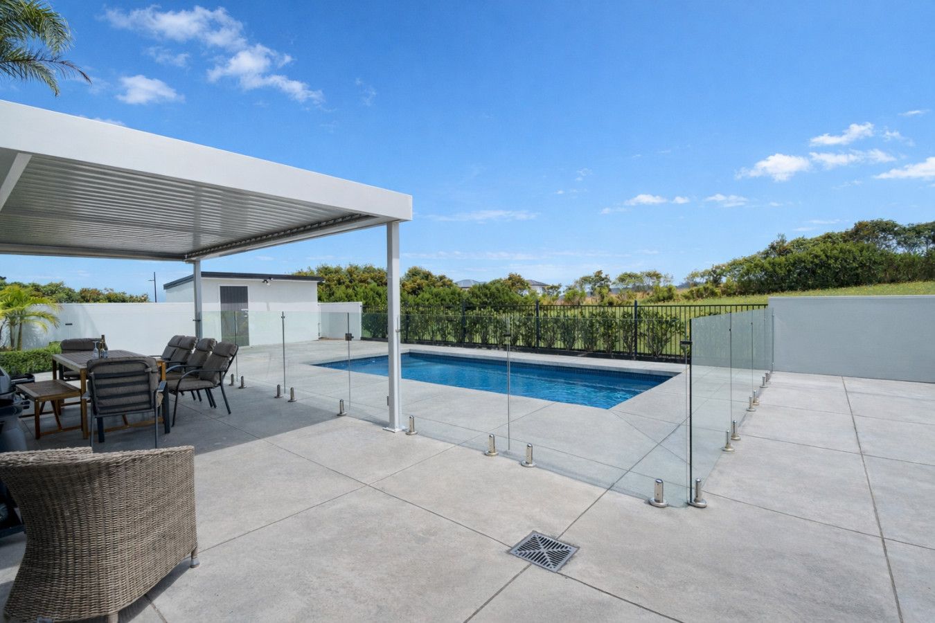 Un espacio al aire libre techado con piscina, mobiliario y un pérgola.